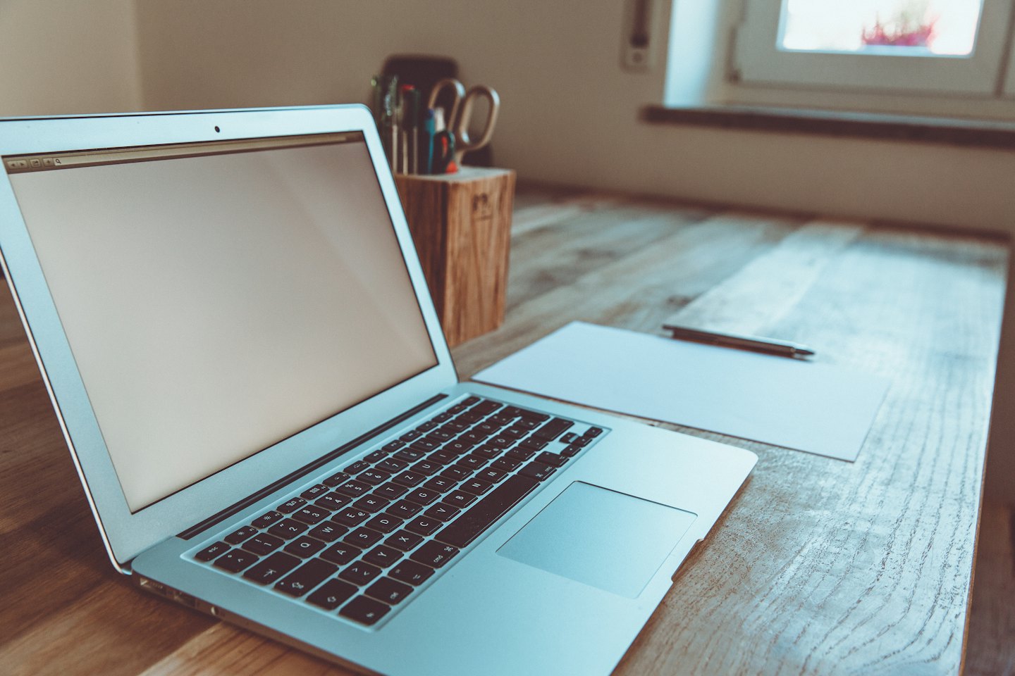 Laptop and office supplies on a wooden desk.