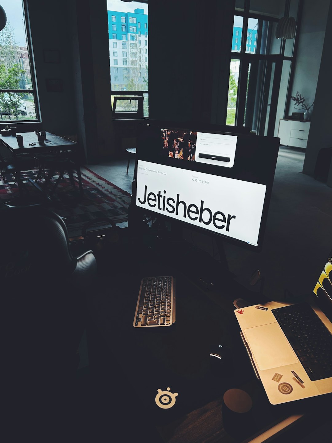 Computer monitor and laptop sitting on a desk in an office.